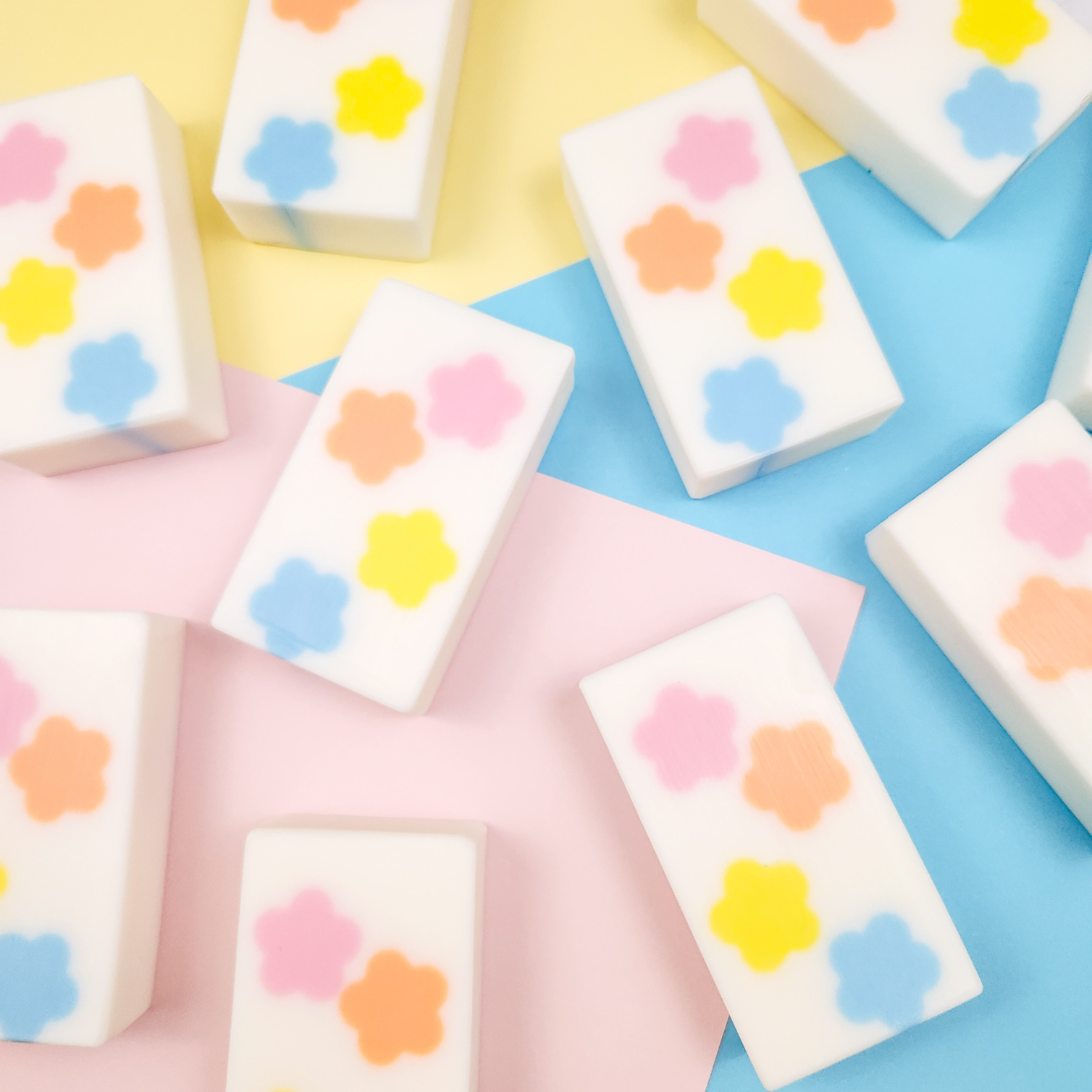 white bar soaps with a colorful flower design. On a multicolored background.