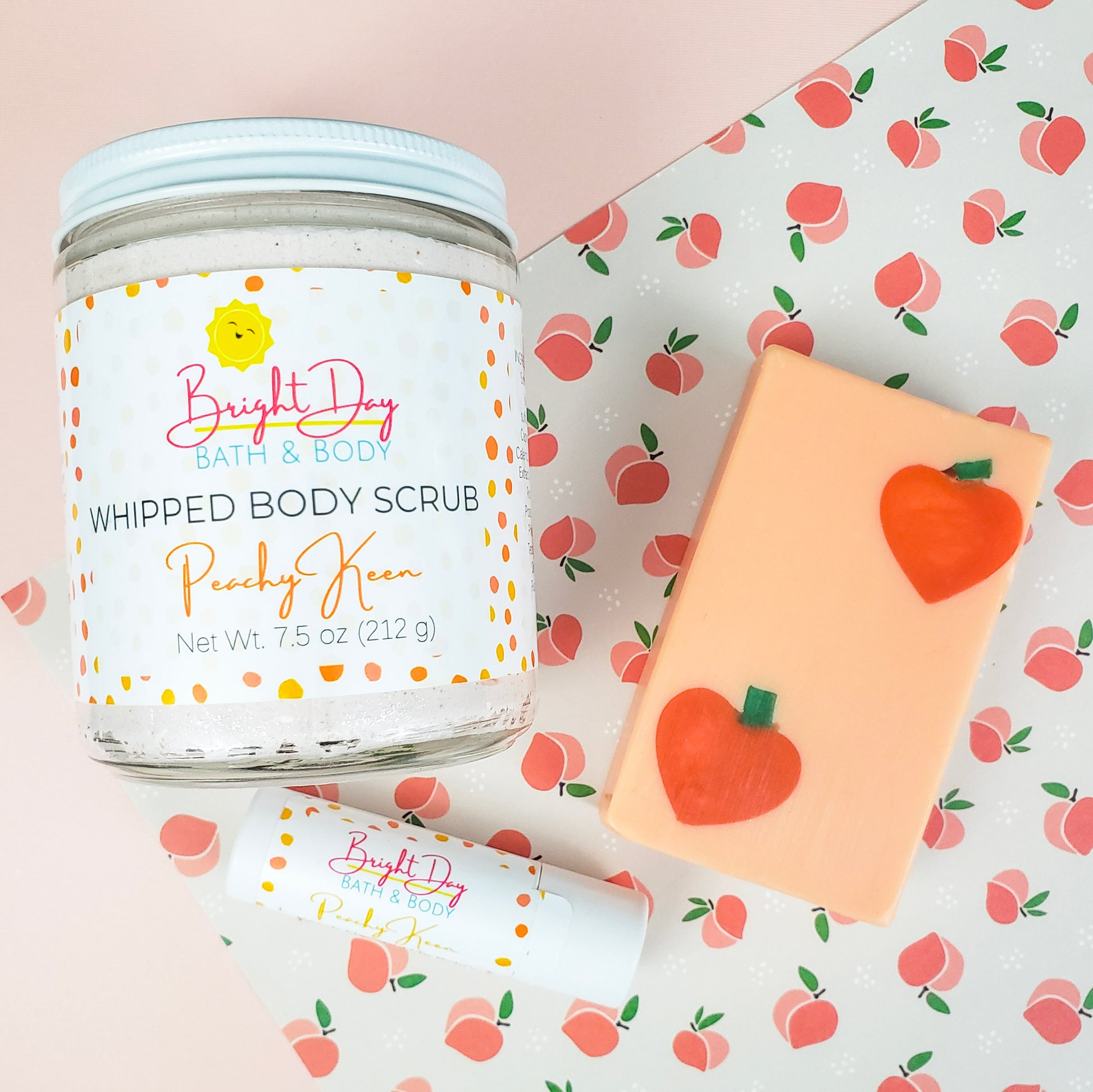 A Jar of Peachy Keen Body Scrub, a Peachy Keen Soap and a Peachy Keen Lip Balm on a peach themed background