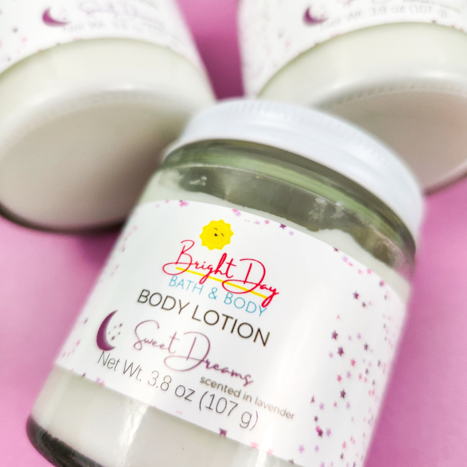 A closeup of the front label of a jar of Sweet Dreams Body Lotion, on a purple background.