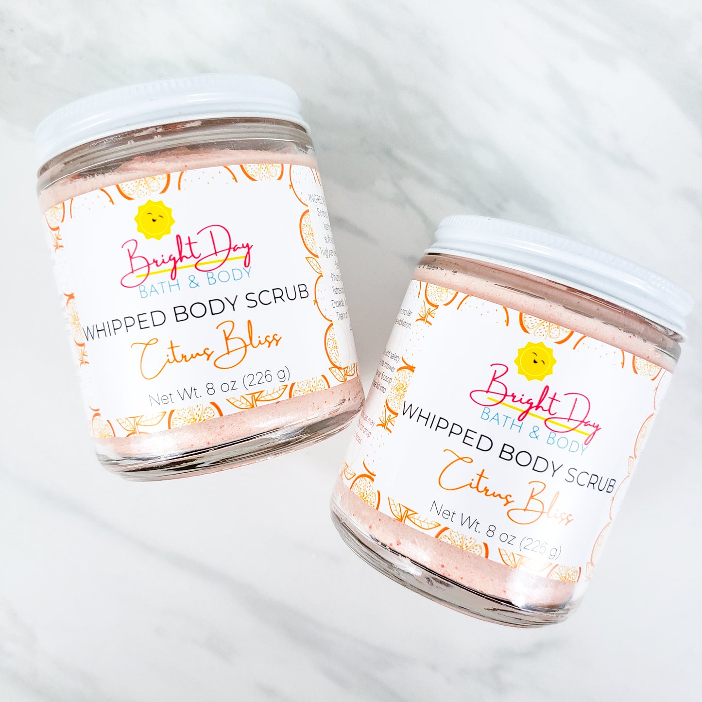 Two Citrus Bliss Body Scrubs on a tile background