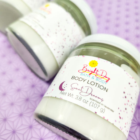 A closeup of two jars of Sweet Dreams Body Lotion on a purple background.