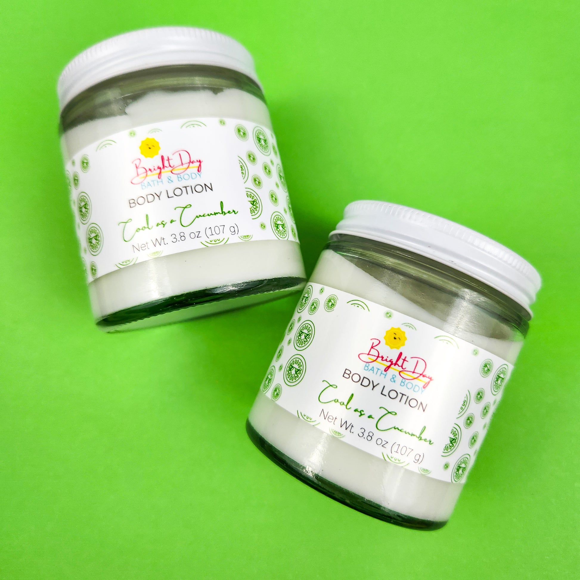 Two jars of Cool as a Cucumber Body Lotion on a green background.