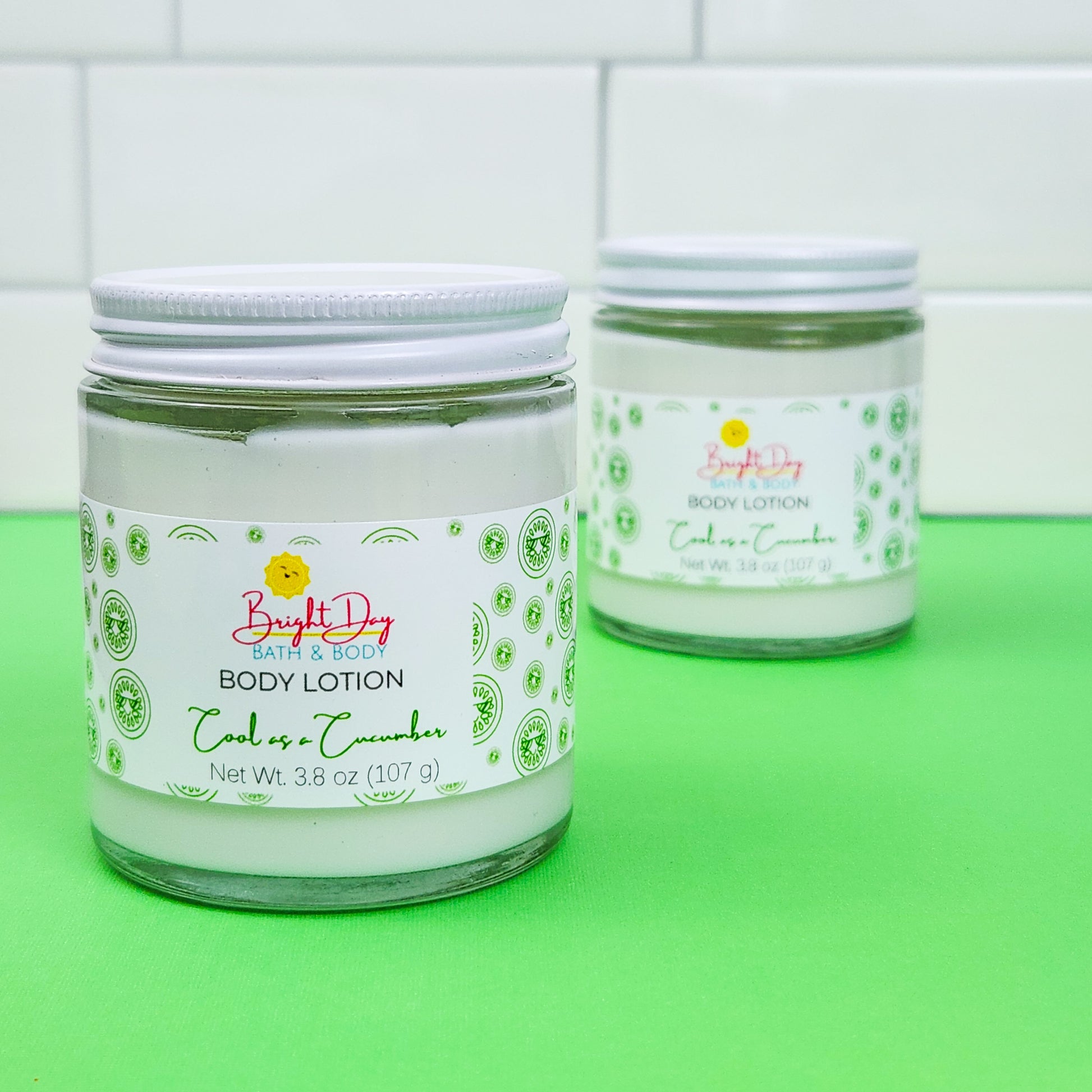 Two jars of Cool as a Cucumber Body Lotion, on a green and white background.