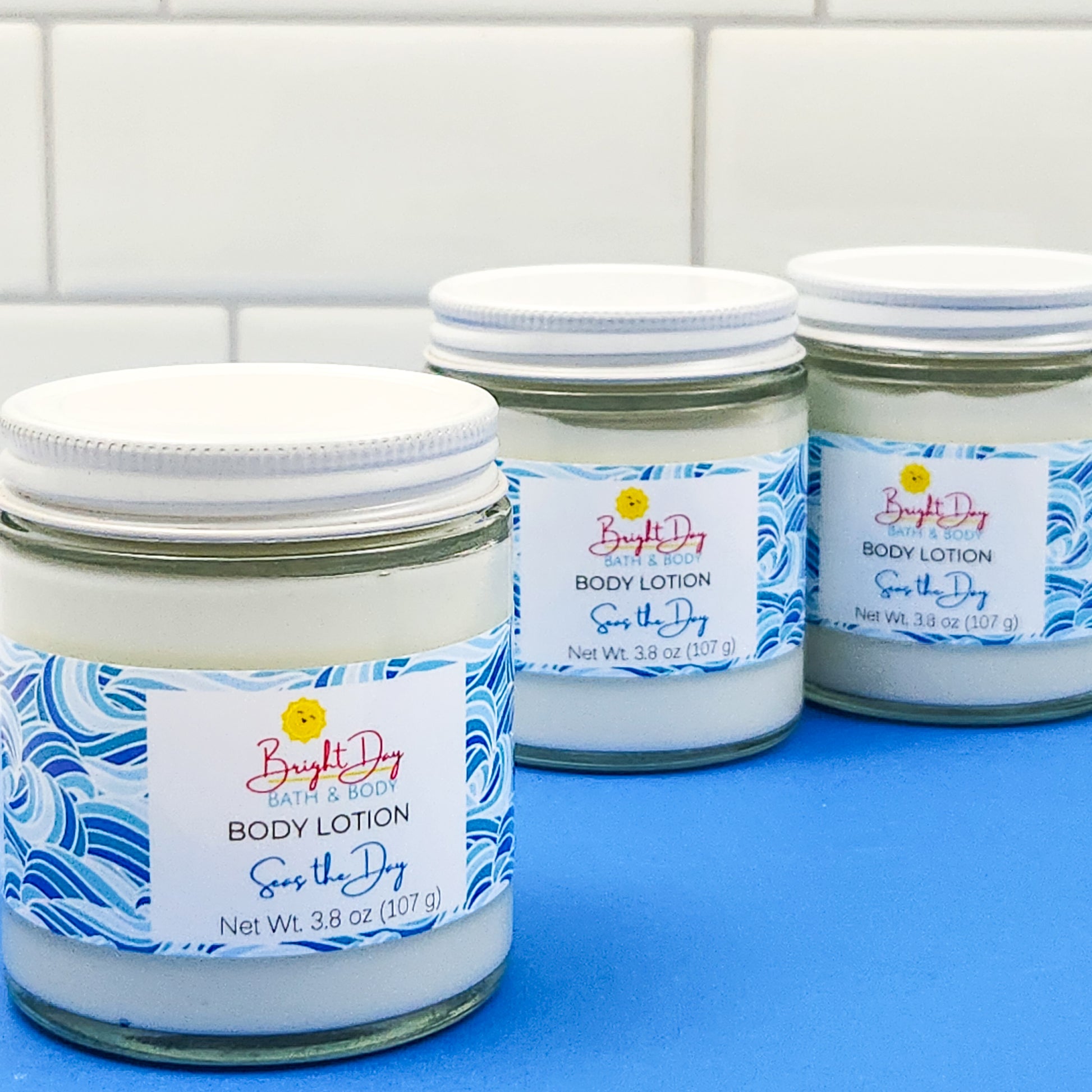 Three jars of Seas the Day Body Lotion on a blue and white background