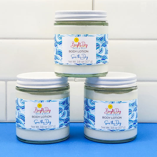 Three jars of Seas the Day Body Lotion stacked like a pyramid on a blue and white background.