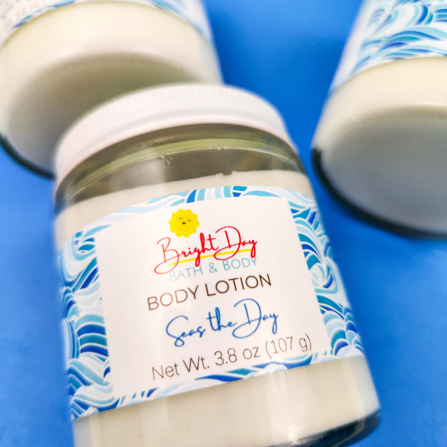 A closeup of a jar of Seas the Day Body Lotion on a blue background