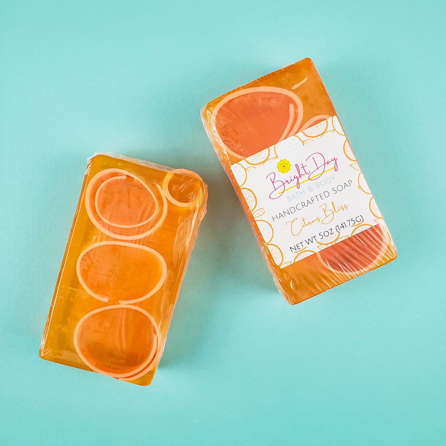 Two transparent orange bars of soap, with dark orange soap curls inside. 