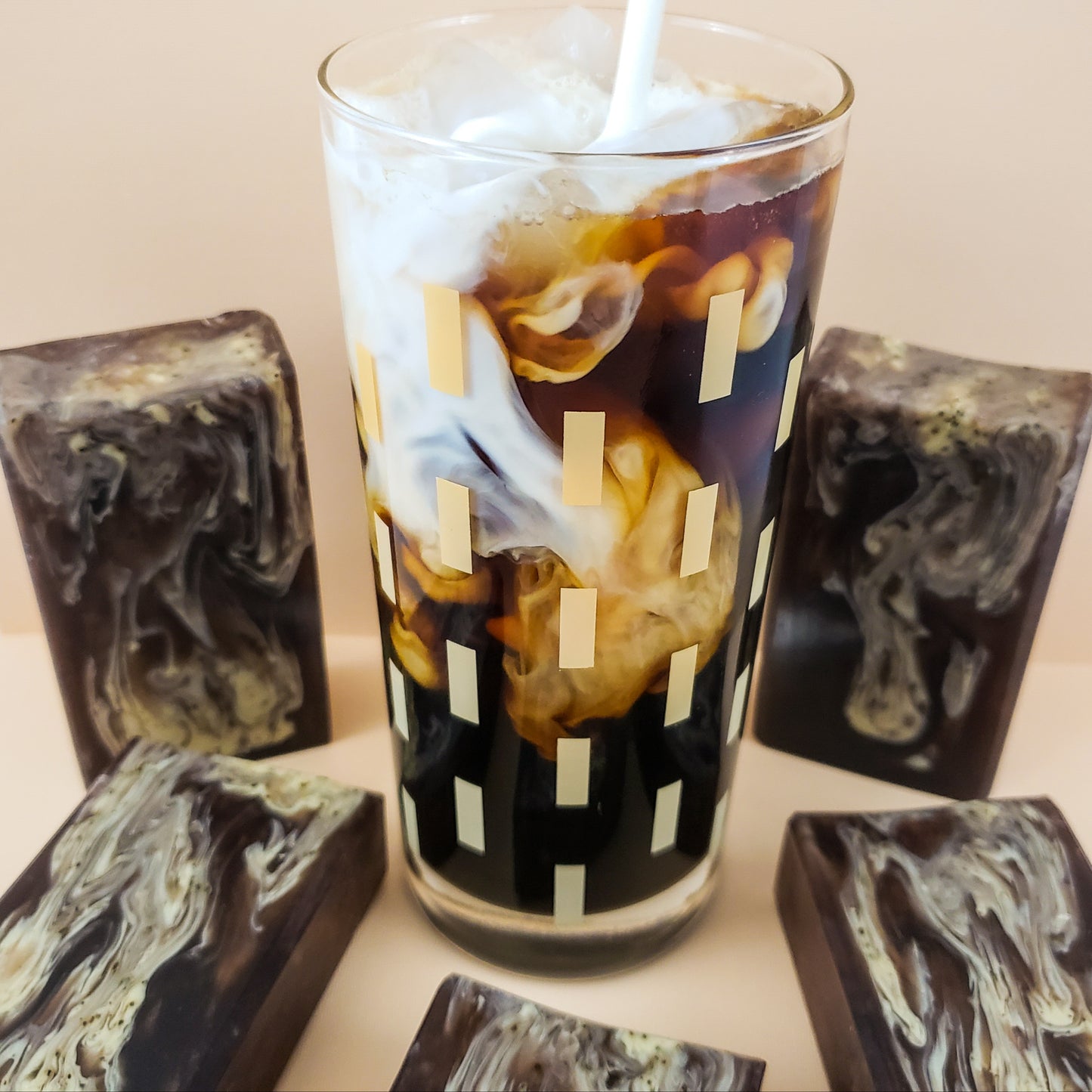 brown bar soaps with light brown swirls surrounding a coffee drink  on a tan background