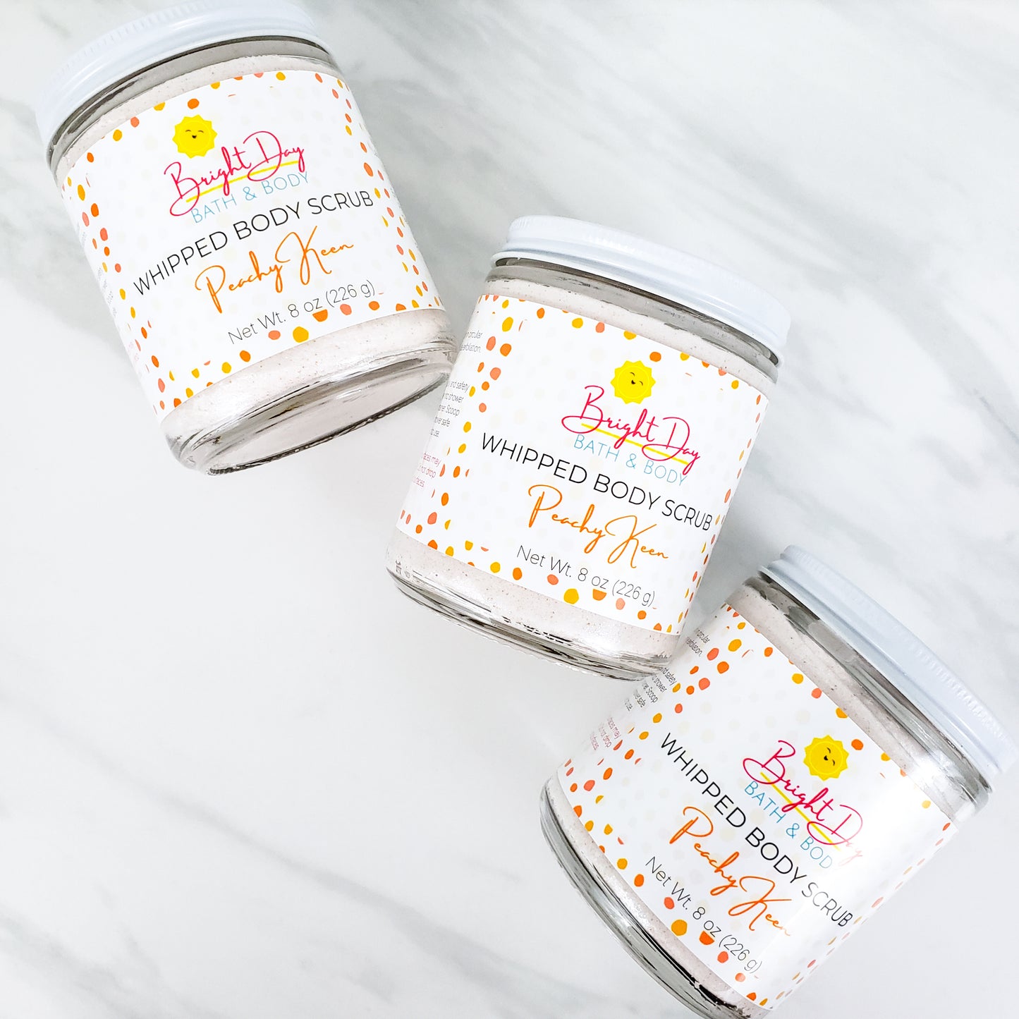 Three Peachy Keen Body Scrubs on a tile background