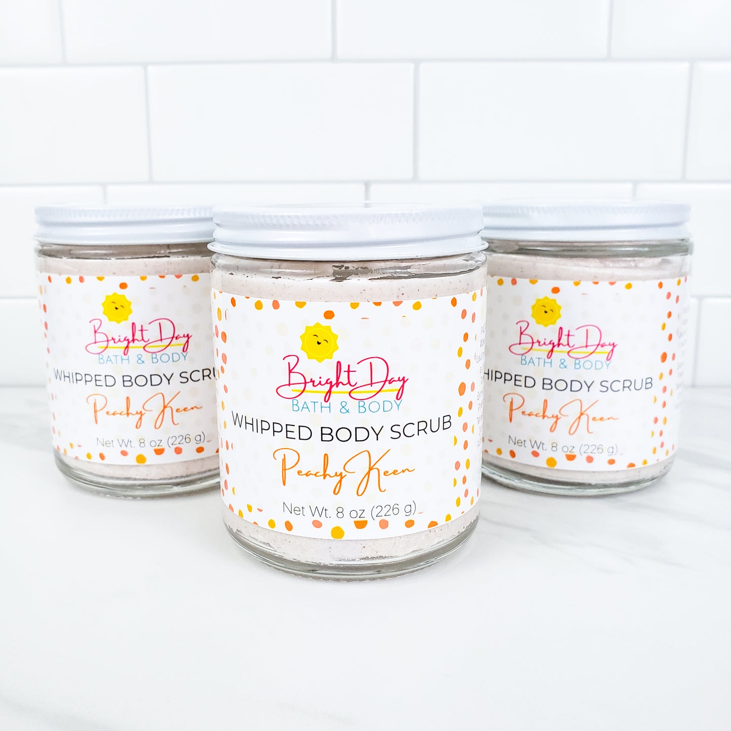 Three Peachy Keen Body Scrubs on a tile background