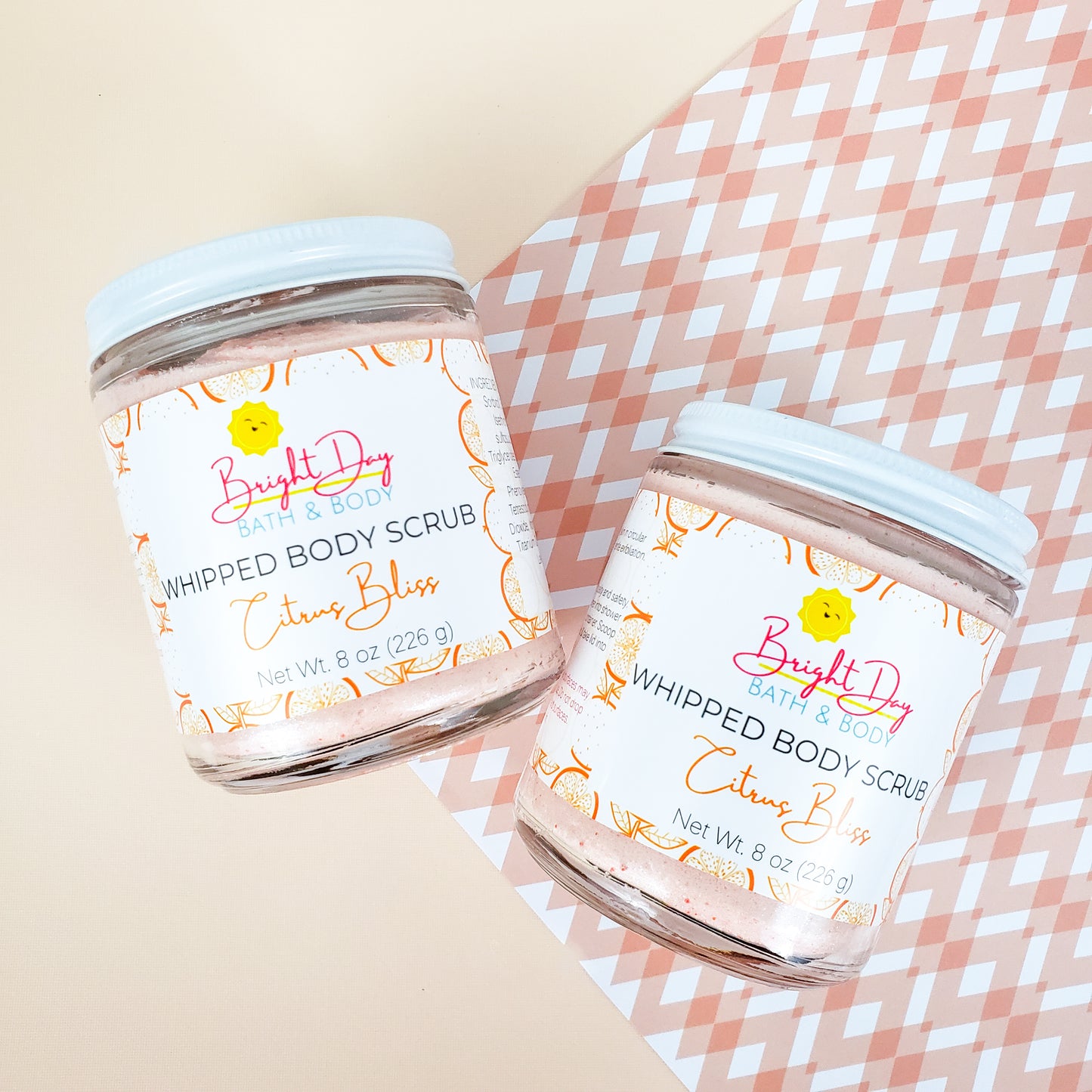 Two Citrus Bliss Body Scrubs on an orange patterned background