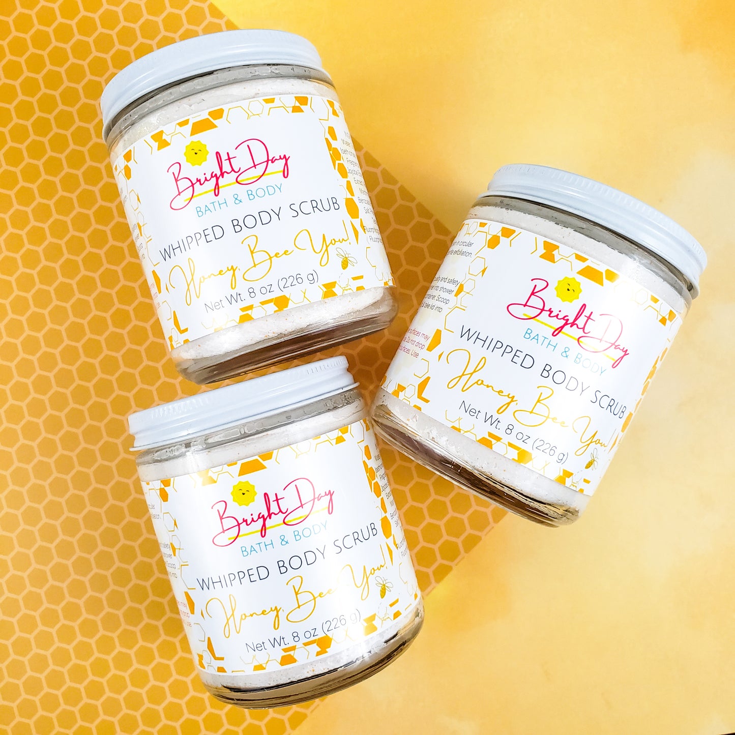 Three Honey Bee You Body Scrub Jars on a golden background