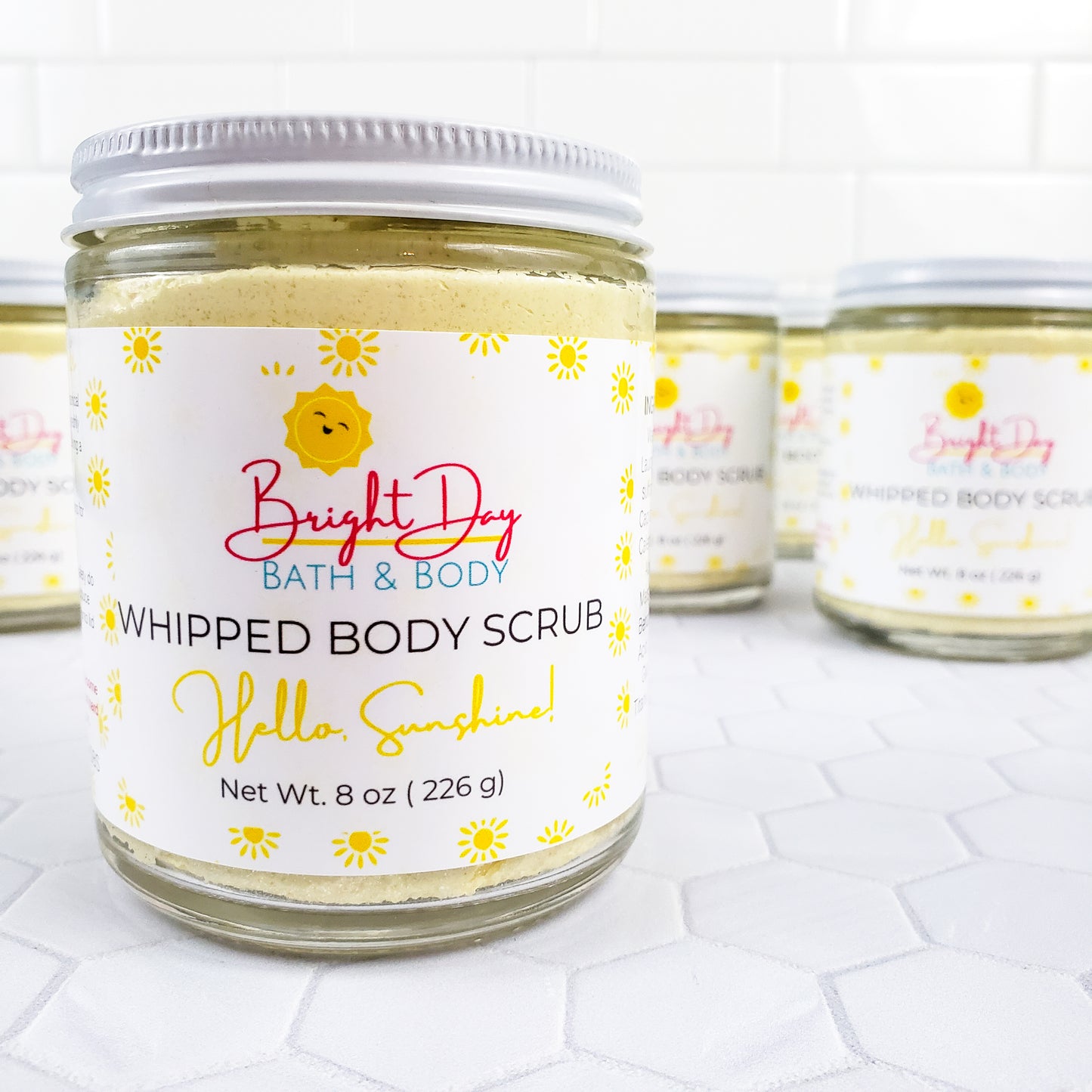 Hello Sunshine Body Scrub Jars on a tile background