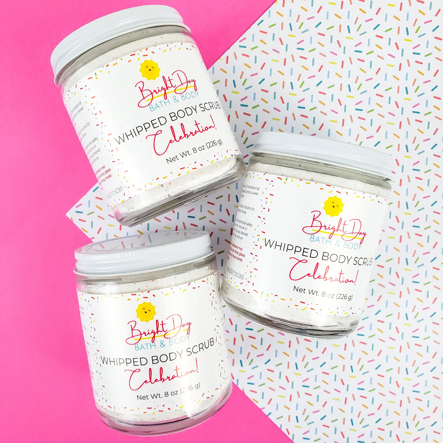 Three Celebration Body Scrub Jars on a confetti and pink background