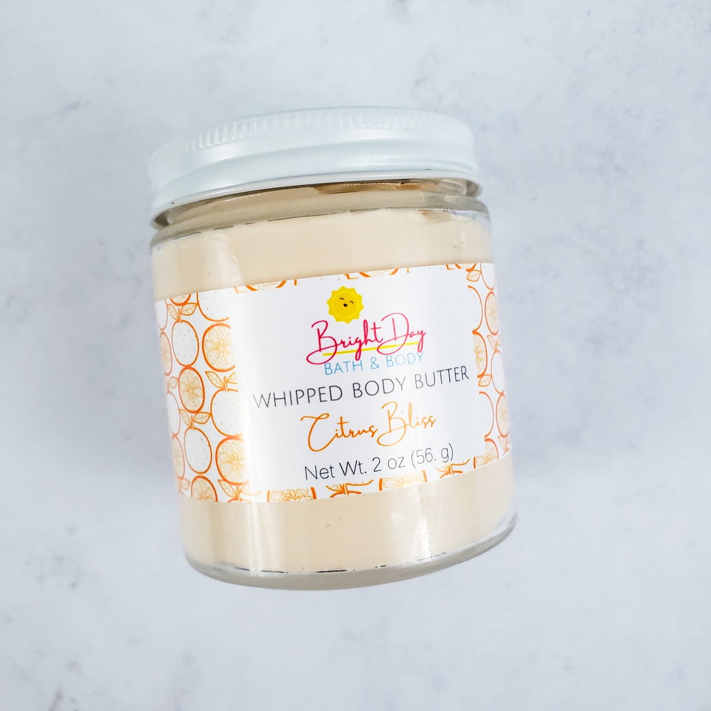 A Citrus Bliss Body Butter jar on a tile background